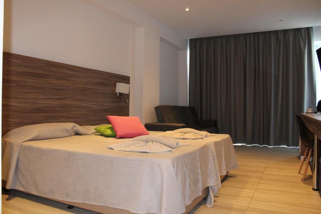 Een hotelkamer met een groot bed, een bureau, een stoel en een raam met gordijnen.