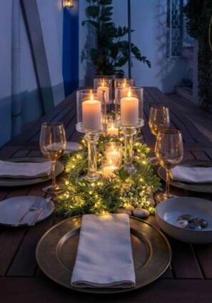 Mesa lista para cenar con velas, copas y una pieza central.