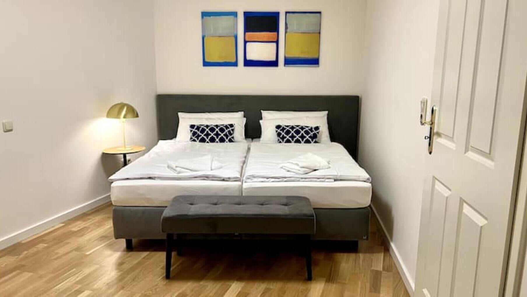 Una camera da letto con un letto, due comodini, una panca e un'opera d'arte appesa al muro.