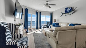 Un salon avec un canapé, un fauteuil et un ventilateur de plafond.