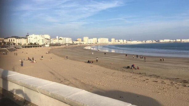 A wide sandy beach with a few people scattered around, a clear sky, and buildings in the background. - Maison Pêcheur Cosy Proche Plage et Port 6pers (Les Sables-d'Olonne)