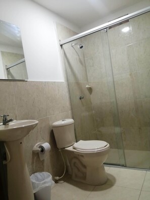 A bathroom with a toilet, sink, and shower.