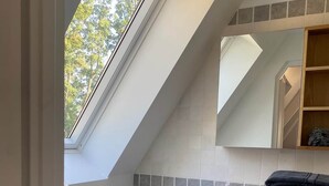 A modern bathroom with a skylight, a toilet, a sink, and wooden cabinets.