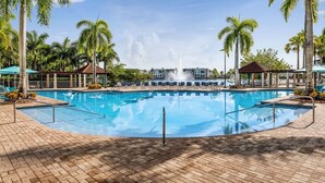 A swimming pool with a fountain, surrounded by palm trees and lounge chairs. - 2BR Villa at Marriott Villas at Doral – Full Kitchen + Golf & Resort Amenities (Miami)