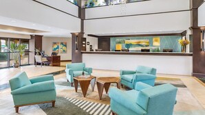 A lobby with teal armchairs, a reception desk, and a large window. - 2BR Villa at Marriott Villas at Doral – Full Kitchen + Golf & Resort Amenities (Miami)