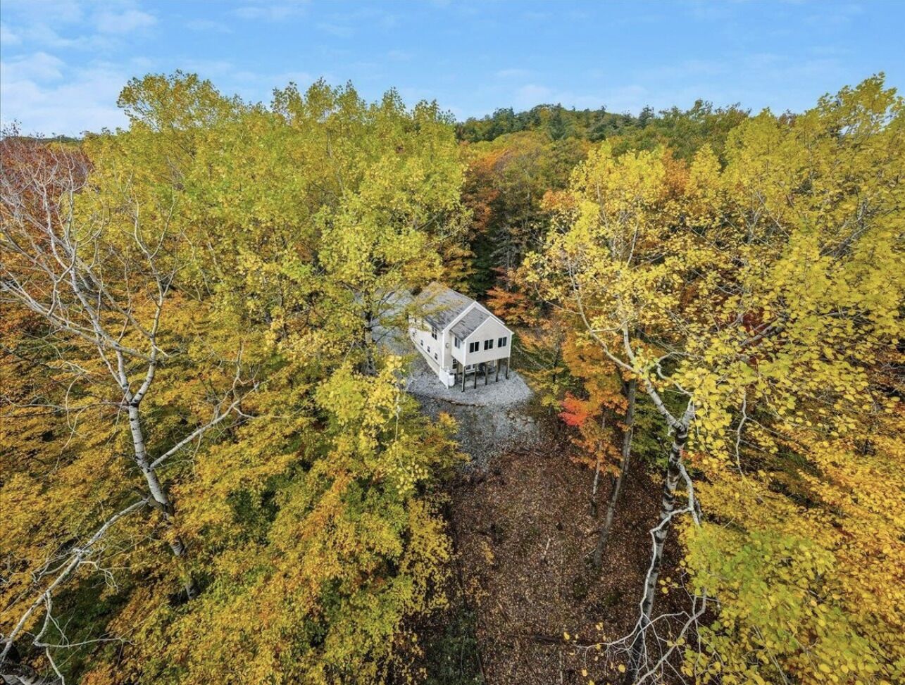 Une maison blanche entourée d’un feuillage automnal.