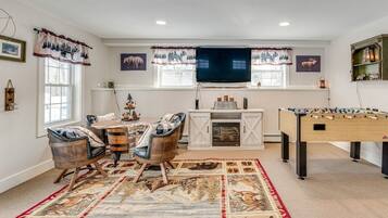 A cozy living room with a fireplace, a foosball table, and a television.