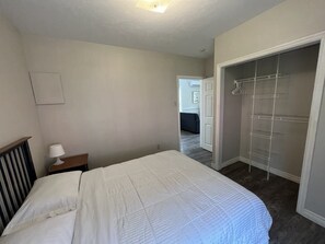 Relax in a cozy retreat with a neatly made bed, bedside table, and spacious walk-in closet.