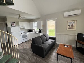 Cozy living space with a kitchenette, sofa, and staircase leading to an upper level.
