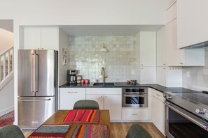 A modern kitchen with white cabinets, stainless steel appliances, and a tiled backsplash.