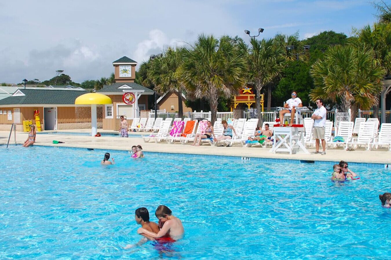 Et poolområde med flere pools, liggestole og et redningstårn.