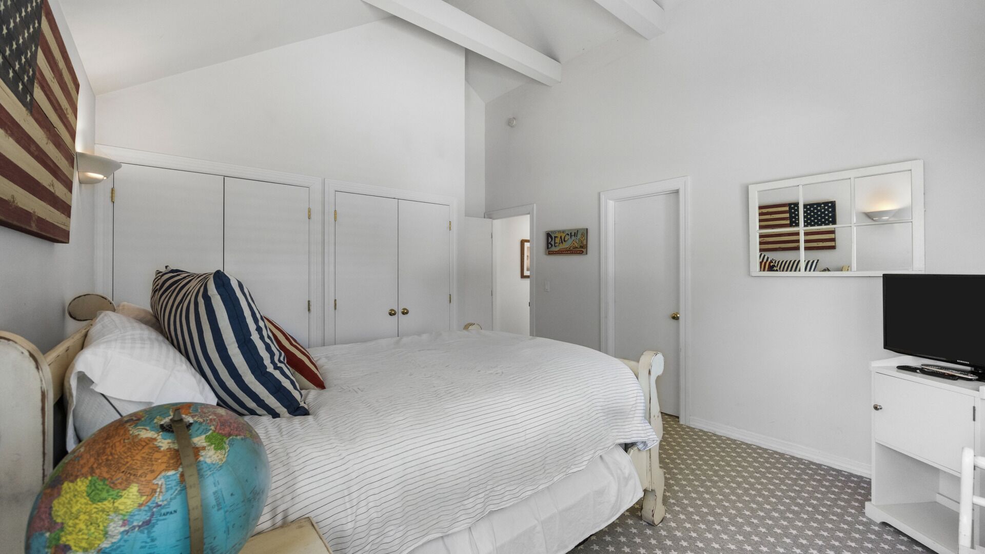 Un dormitorio con cama, un globo terráqueo, un televisor y una pared con una bandera y un letrero.