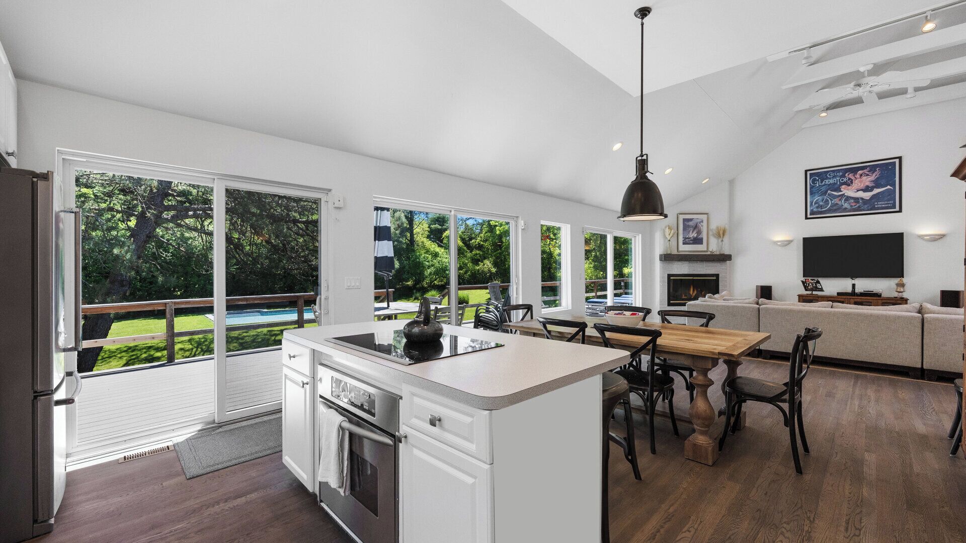 A modern kitchen with a large island, sliding glass doors to a backyard, and a dining area with a view of the outdoors.