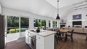 A modern kitchen with a large island, sliding glass doors to a backyard, and a dining area with a view of the outdoors. - Spacious Southampton Home in Shinnecock Hills, Central Between Southampton,... (Southampton)