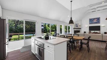 A modern kitchen with a large island, sliding glass doors to a backyard, and a dining area with a view of the outdoors.