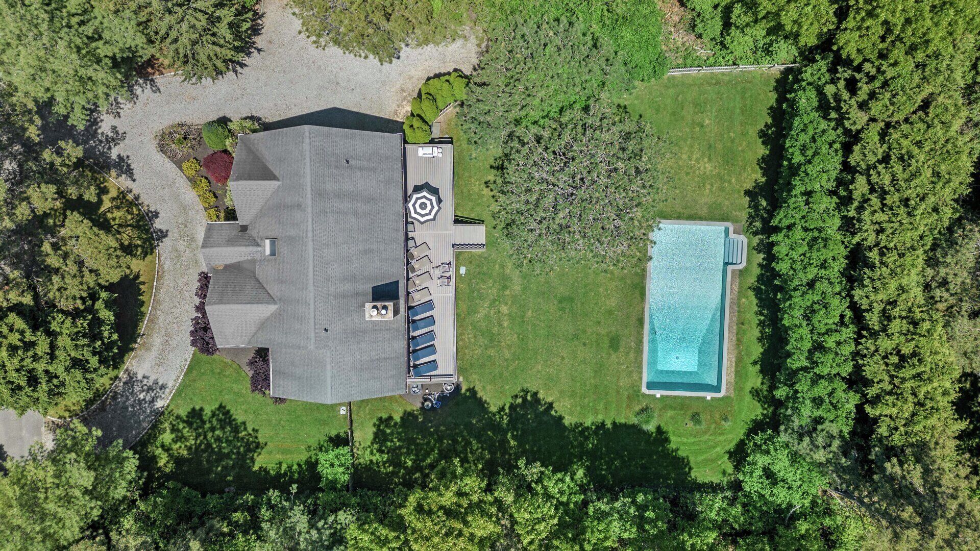 Vista aerea di una casa con un'ampia terrazza, una piscina e vegetazione circostante.