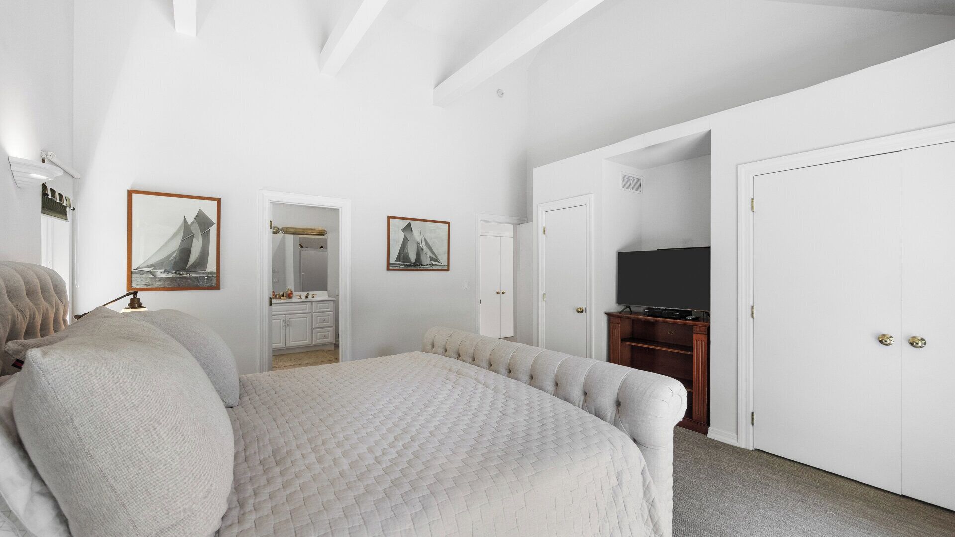 Une chambre à coucher avec un lit, une commode, un téléviseur et deux portes.