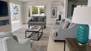 A modern living room with a grey sofa, a coffee table, and a teal lamp. - Luxury 4 Bed Villa in Barbados With Amazing Views (Bridgetown)