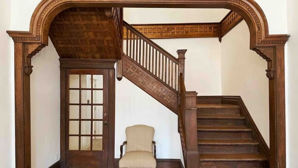 A wooden staircase with a curved design, leading to an upper floor. - Spacious and Modern Apt in Downtown Evansville in a Historic Victorian Home (Evansville)