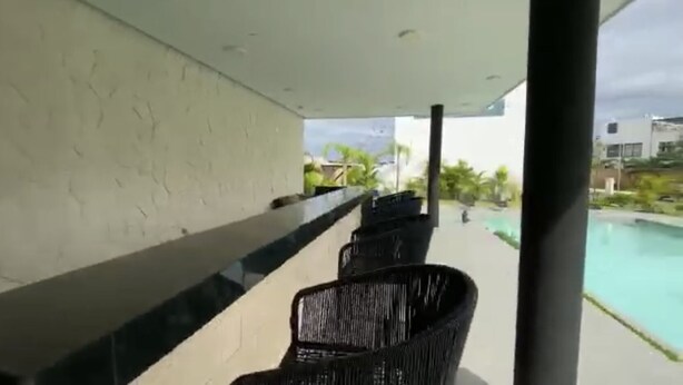 Un balcón con vista a una piscina, una silla y una pared blanca con textura.