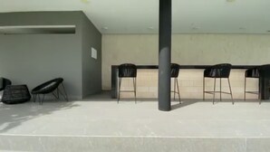 Un espacio interior moderno con una mesa larga y cuatro sillas, un pilar y una pared con un pequeño letrero.