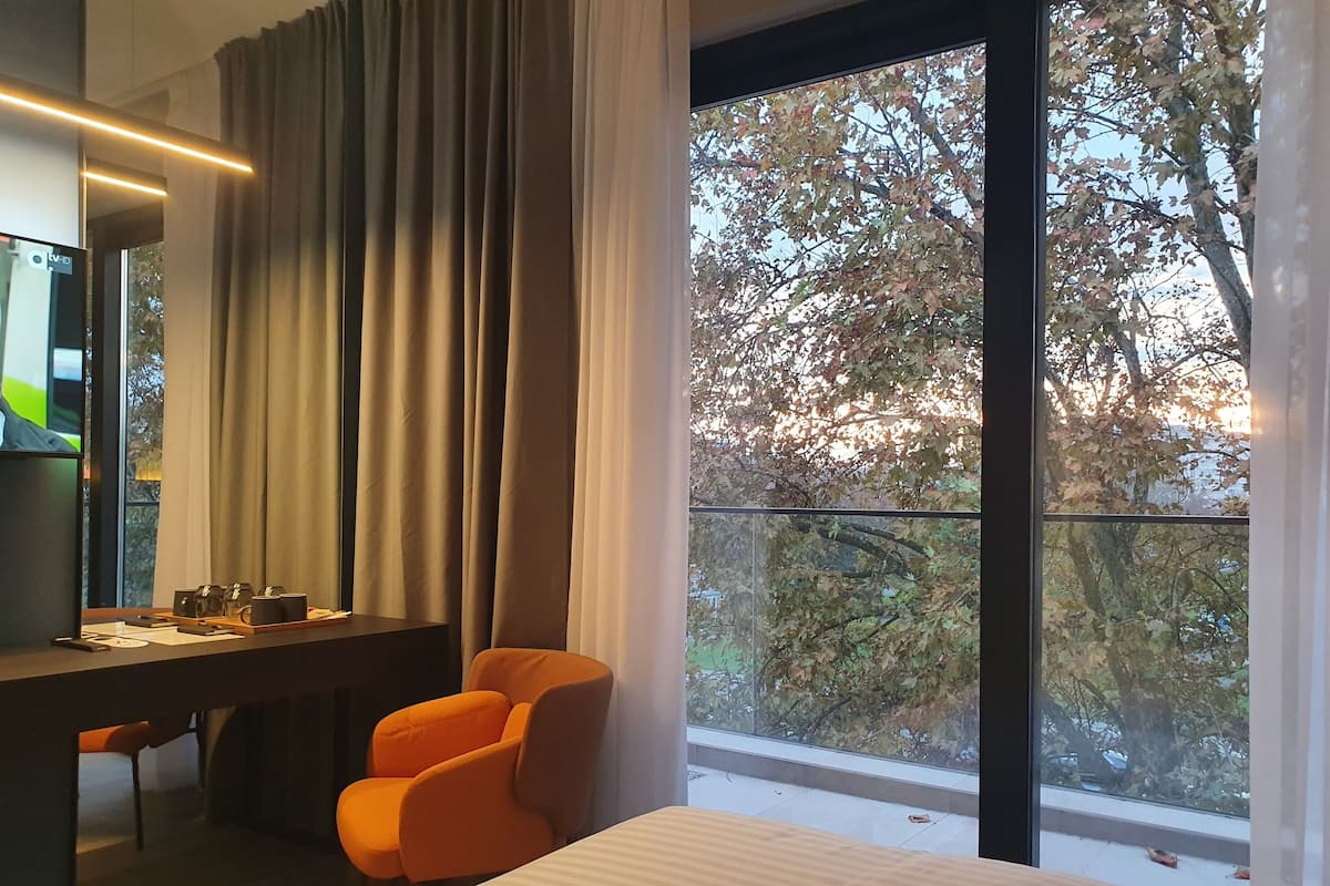 Una habitación de hotel con un ventanal grande, un escritorio con silla y una cama.
