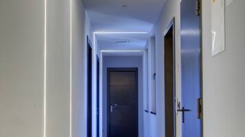 Un corridoio con una luce a soffitto, una porta con un numero e un segnale di uscita di emergenza.
