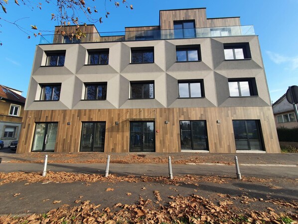 A modern multi-story building with a geometric facade, large windows, and a wooden panel accent. - Avenue21 (Zagreb)