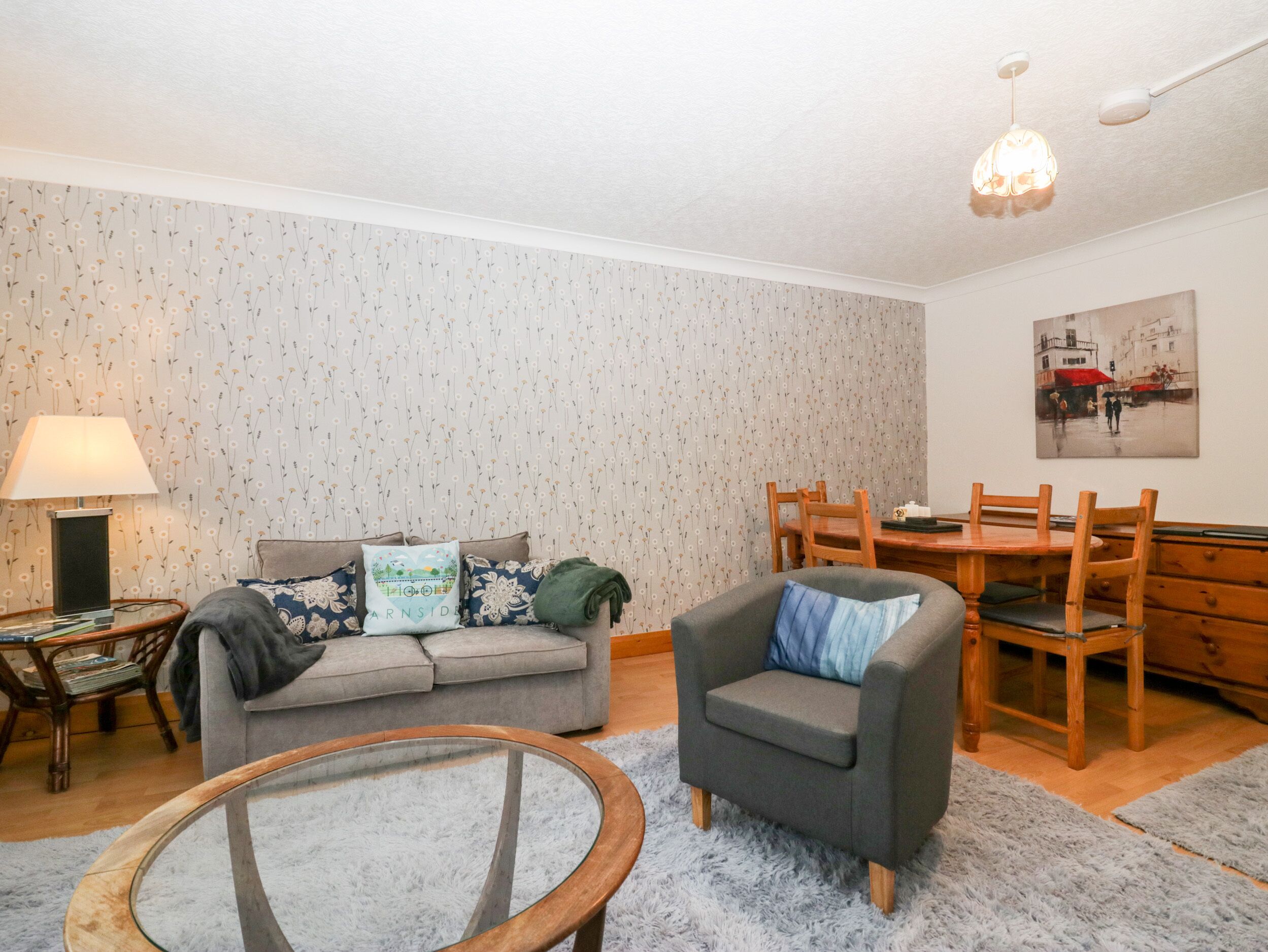A cozy living room with a sofa, armchair, and a dining table.
