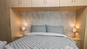Un dormitorio con cama, dos mesitas de noche y un armario.