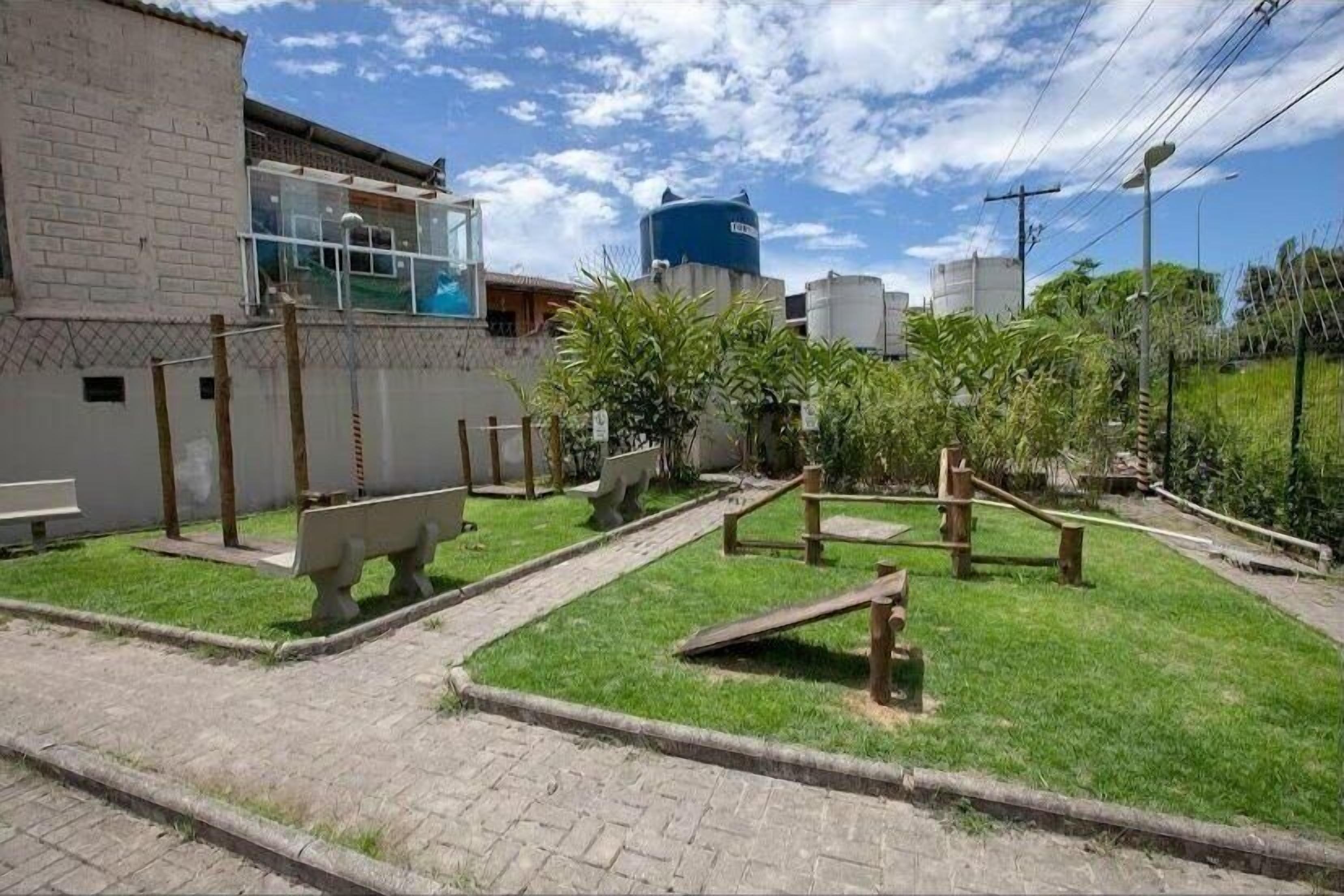 A courtyard with a brick wall, a bench, and a water tank.