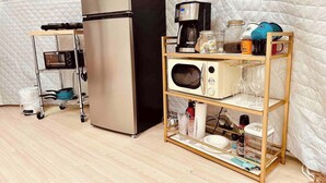 A compact kitchenette with a stainless steel refrigerator, a microwave, a coffee maker, and a glass jar on a wooden shelf. - The Perch: Glamping by Rafting (Cosby)