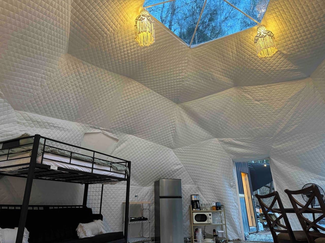 A tent-like interior with a bunk bed, a refrigerator, and a small kitchenette.