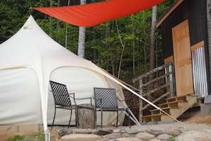 Una carpa con dos sillas, una terraza de madera y una escalera que lleva a un edificio.