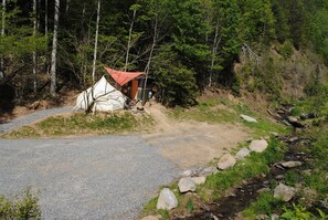 A tent set up on a gravel path with a stream nearby.