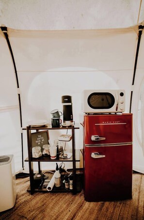 A compact kitchenette with a microwave, coffee maker, and a red refrigerator. - Mimosa Hill @ Wanderlust Woods (Cosby)