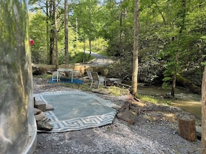 Un espace extérieur rustique agrémenté d’un chemin de pierre, d’un tapis à motifs et d’un banc.