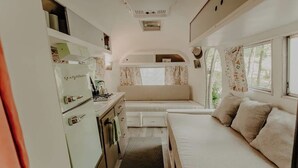 Ein kompaktes Wohnmobil-Interieur mit einer Küchenzeile, einem Essbereich und einer Schlafkabine.