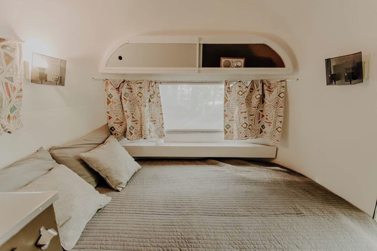 A cozy bedroom with a built-in window seat, a bed, and a small table.