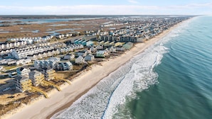 Une zone résidentielle côtière, avec des maisons le long de la plage, un ciel dégagé et aucune commodité visible.