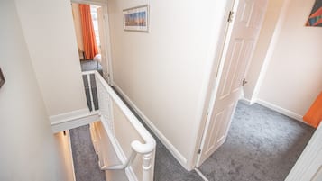 A hallway with a carpeted floor, a white door, and a picture on the wall.