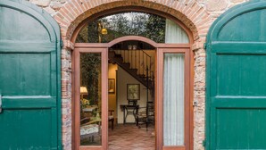 A doorway with a wooden frame and glass panels, leading to a staircase and a room with a table, chairs, and a lamp.