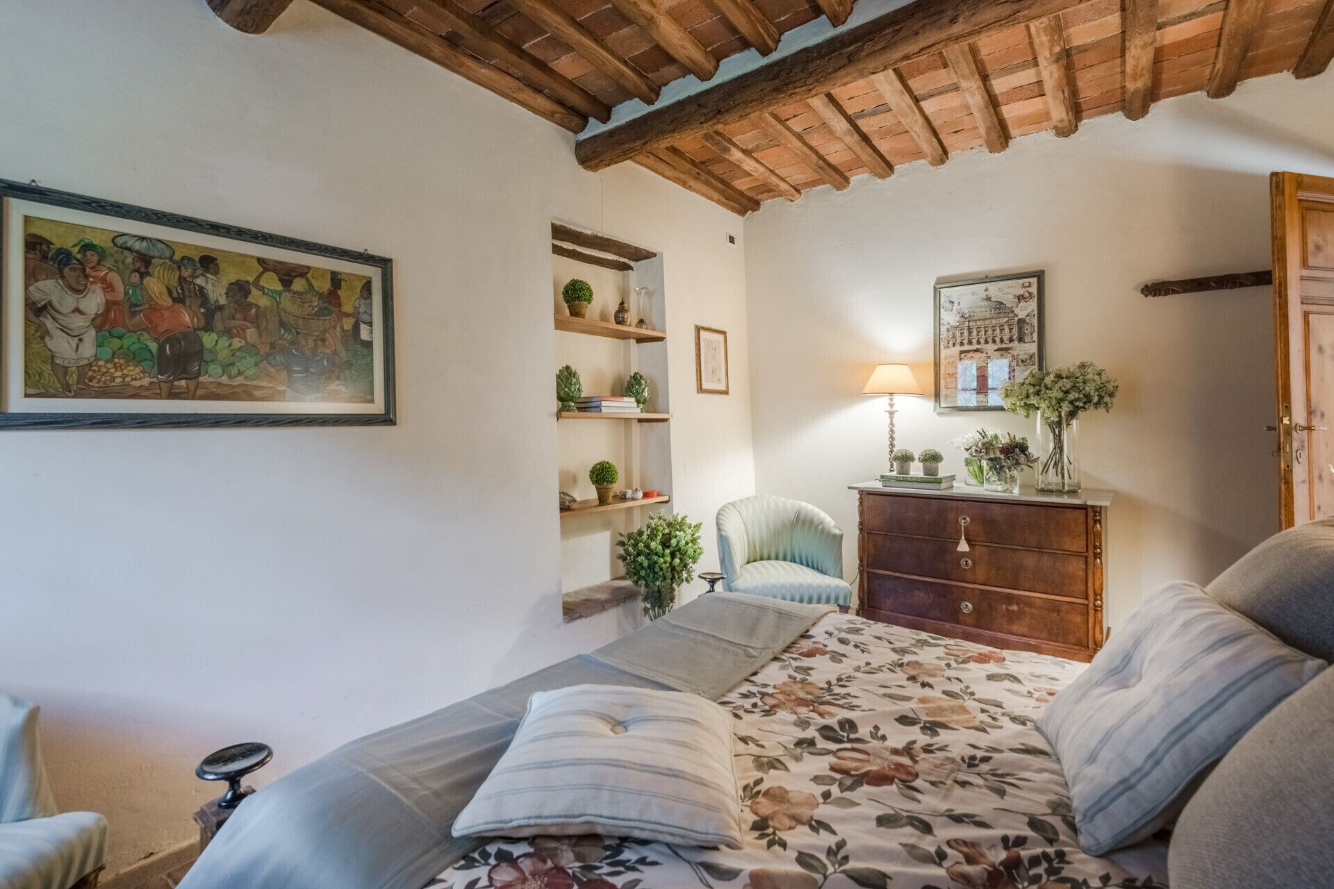 Una camera accogliente con un letto, una sedia, un comò in legno e mensole con piante e libri.