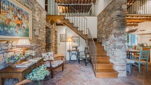 A spacious interior with a stone staircase, wooden furniture, and a painting on the wall.