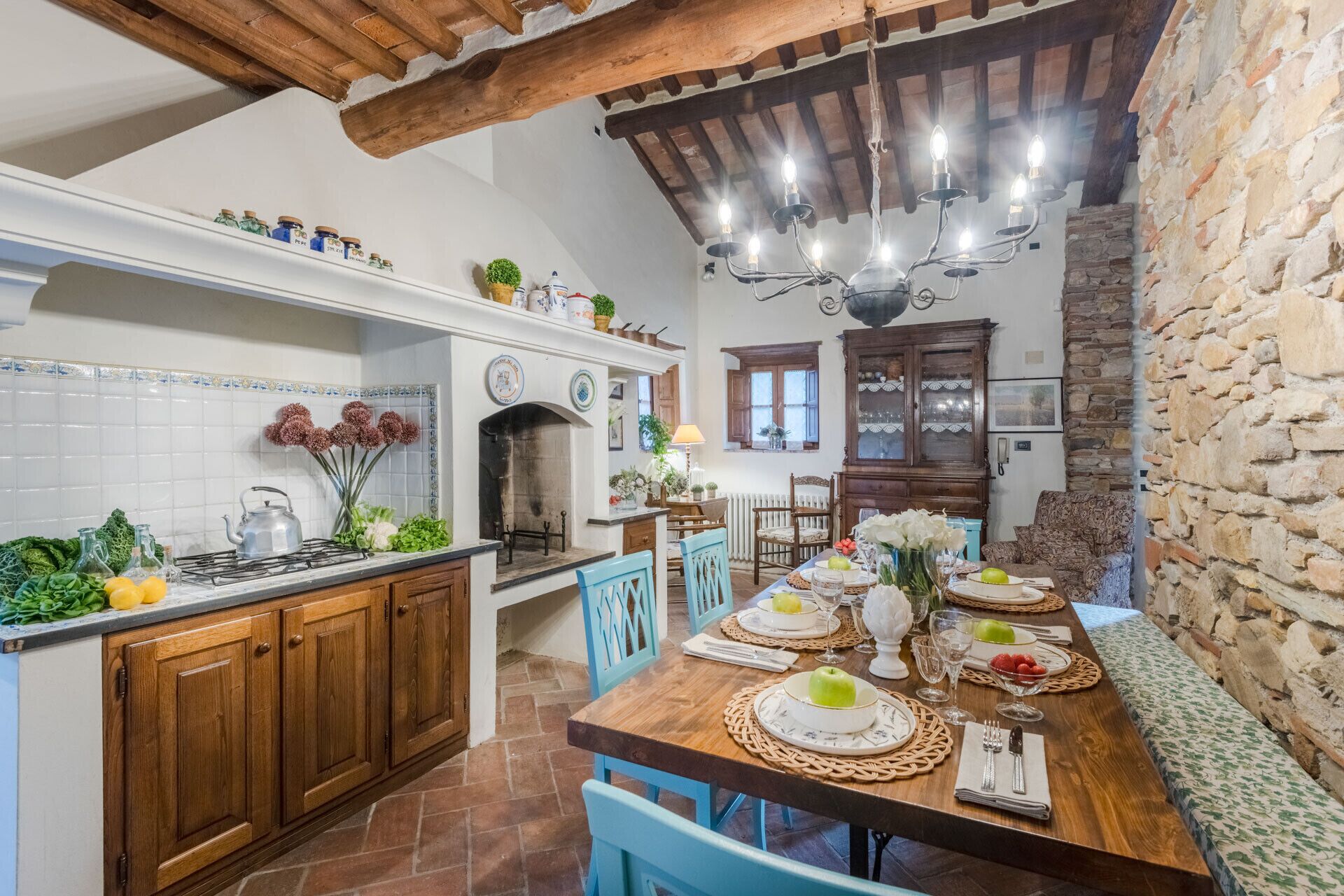 A rustic kitchen with wooden cabinets, a tiled backsplash, and a stone wall.