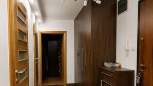 Ein Flur mit Holztüren, einem dunklen Schrank und einem gefliesten Boden.