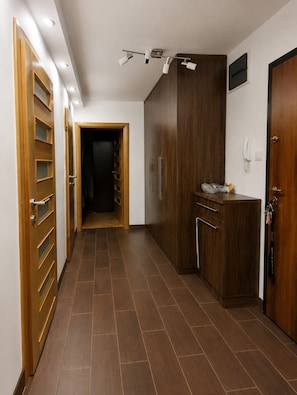 Ein Flur mit Holztüren, einem dunklen Schrank und einem gefliesten Boden.