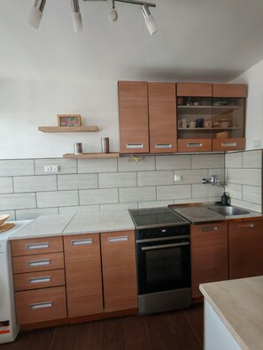 Eine moderne Küche mit Holzausstattung, integriertem Backofen, Spüle aus Edelstahl und einer helffen Arbeitsplatte.