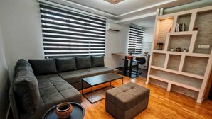 Ein modernes Wohnzimmer mit einem Ecksofa, einem Couchtisch, einem Hocker und einer eingebauten Bücherreol.