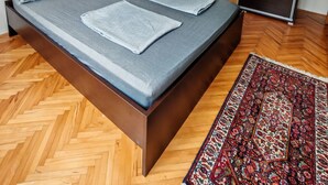 Ein modernes Schlafzimmer mit einem hölzernen Bett, einem Spiegel und einem gemusterten Teppich.
